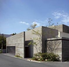 the building is made out of concrete and has two garages on each side, with trees growing in front of it