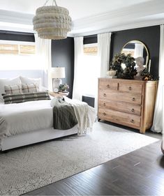 a bedroom with black walls, white bedding and wooden dresser in the center area