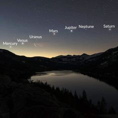 the night sky is lit up with stars and planets above a body of water, surrounded by mountains