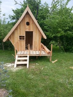 there is a small wooden house built in the grass with stairs leading up to it