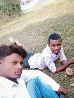 two young men laying on the ground next to each other