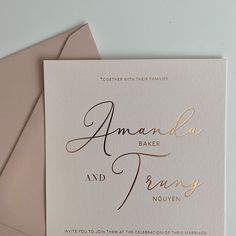 the wedding stationery is displayed on top of two envelopes, with gold foil lettering