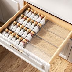 an open drawer with spices in it on top of a wooden floor next to a white refrigerator