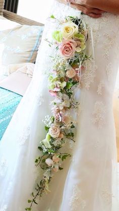 a woman in a wedding dress holding a bouquet of flowers on her waist and wearing a white bridal gown