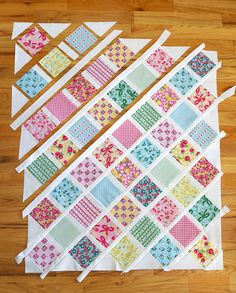 several pieces of quilting laid out on a wooden floor with one piece cut into squares