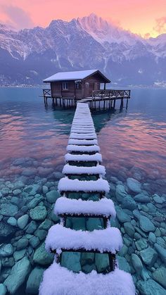 a dock with snow on it and a cabin in the background at sunset or dawn