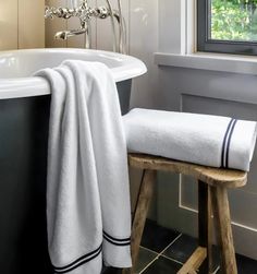 a white towel sitting on top of a wooden stool next to a bath tub