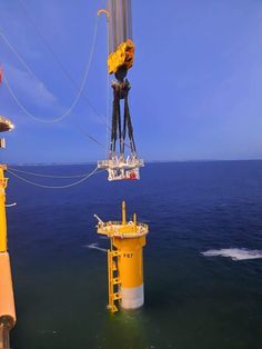 a crane is suspended over the ocean by two yellow buoys with ropes attached to them