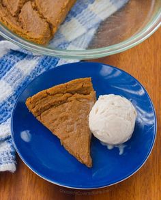 a piece of pie on a blue plate next to a scoop of ice cream in a bowl