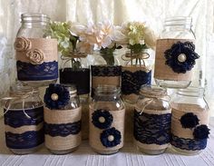 mason jars decorated with burlocks and lace are sitting on a table next to flowers