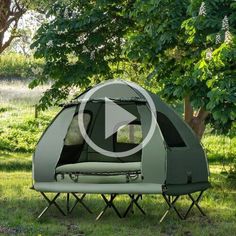 a tent set up in the grass near trees