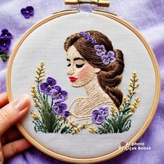 a woman's face with flowers in her hair is embroidered onto a purple fabric