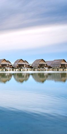 a row of huts sitting on top of a beach next to the ocean