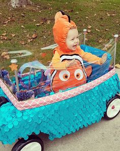 a baby in a toy car with an orange and blue fish on it's back