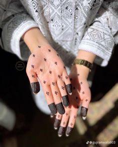 a woman's hands with black nail polish and stars on her nails, holding onto a chair