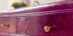 a purple dresser with brass handles and knobs