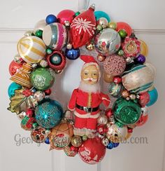 a christmas wreath with ornaments hanging on the front door