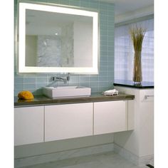 a bathroom with blue tiles and a white sink under a large mirror above the counter