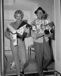 an old black and white photo of two people in pajamas holding boxes with packages on them