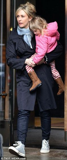 a woman holding a child in her arms while walking out of a building with another person