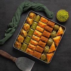 a pan filled with pastries next to a knife and green napkin on top of a table