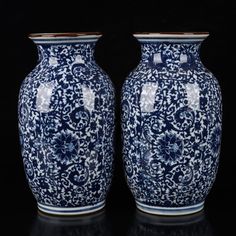 two blue and white vases sitting next to each other on a black table top