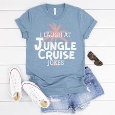 a shirt that says i laugh at jungle cruise jokes next to some shoes and sunglasses