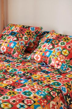 a bed with colorful sheets and pillows on it