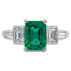 Ring contains one center emerald shape emerald 1.25ct, two straight baguette diamonds and two tapered baguettes, 0.78tcw. Diamonds are G in color and VS2 in clarity. Center stone is mounted in a handmade basket prong setting and side diamonds are mounted in bezel settings. Ring is a size 6.25 and can be resized to desired measurement. Please request customization. All of our pieces are packaged carefully and accompanied by a Pico box to keep your jewelry item safe. A complimentary appraisal can Classic Green Diamond Ring With Baguette Diamonds, Gia Certified Baguette Cut Emerald Ring, Green Emerald Cut Emerald Ring With Baguette Diamonds, Classic Green Emerald Ring With Baguette Diamonds, Green Emerald Ring With Three Stone Baguette Cut, Green Baguette Cut Three Stone Emerald Ring, Green Emerald Ring With Baguette Diamonds, Art Deco Platinum Emerald Cut Emerald Ring, Green Emerald-cut Jewelry With Diamond Accents