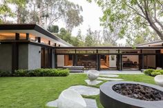 the modern house is surrounded by lush green grass and stone steppings that lead to an outdoor fire pit