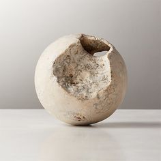 a white vase sitting on top of a table next to a gray wall and floor