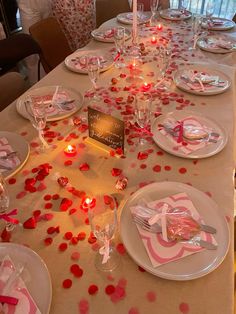 a table set with plates and candles for a valentine's day dinner or party