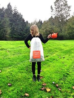 a woman standing in the grass holding an orange object