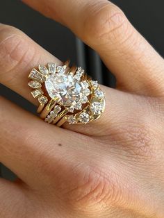 a woman's hand with a diamond ring on top of her finger and an engagement band