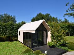 a small house sitting in the middle of a lush green field with trees and bushes