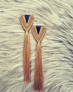 a pair of earrings with tassels hanging from them on a fur surface,