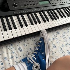 someone is wearing converse shoes while sitting in front of an electronic keyboard and playing the piano