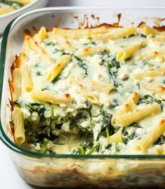 a casserole dish with spinach, cheese and pasta in it on a table