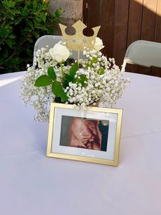 a vase with baby's breath flowers in it and a photo frame on the table