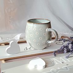 a coffee cup sitting on top of a table next to some cut outs and flowers