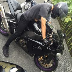 a man on a black motorcycle with purple rims is leaning over the wheel well