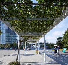 people are walking around in the park with umbrellas and trees on either side of the walkway