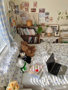 a laptop computer sitting on top of a bed next to a book shelf filled with books