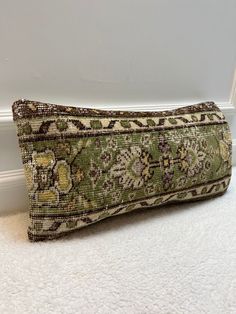 a green and beige pillow sitting on top of a white floor next to a wall