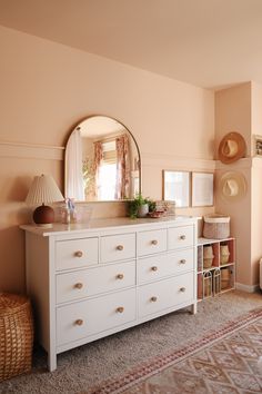 a white dresser sitting next to a mirror on top of a wall