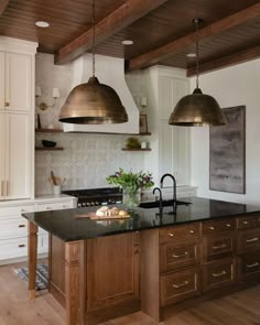 a kitchen with an island and two pendant lights above the stove top, along with white cabinets