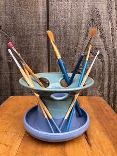 a blue bowl filled with lots of toothbrushes on top of a wooden table