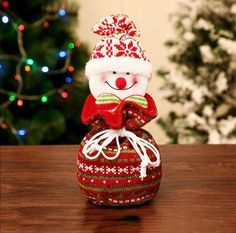 a small snowman sitting on top of a red and green christmas ornament