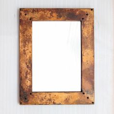 an old rusty metal frame hanging on the wall with a white blank space in it