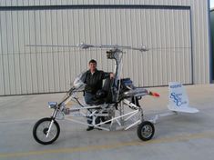 a man sitting on top of a motorcycle with a helicopter attached to the front wheel